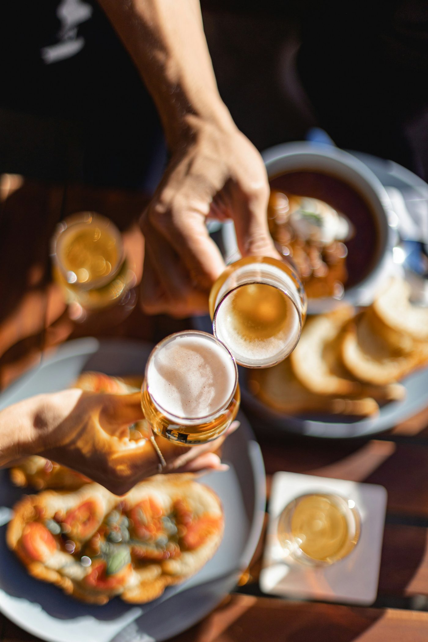 Friends toasting craft beers around a table of food